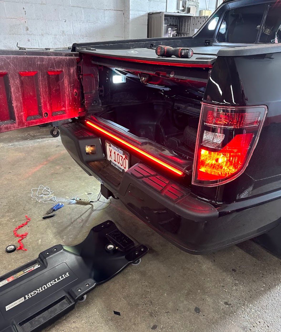 Black pickup with a red LED light bar installed across the tailgate